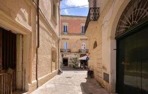 an alley in an old town with a dog sitting in the doorway at Elena Suites - Boutique Apartments in Lecce