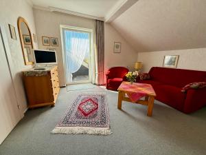 a living room with a red couch and a tv at Pension Hansen auf Fehmarn in Fehmarn