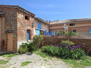 a brick house with a retaining wall and purple flowers at La maisoun d'odette in Mérenvielle