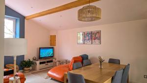 a living room with a dining room table and a television at La maisoun d'odette in Mérenvielle