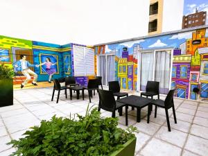 a patio with tables and chairs in front of a mural at Link Cordoba Hostel in Cordoba