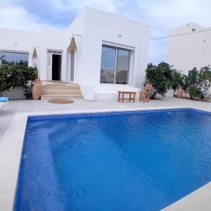 a swimming pool in front of a house at Villa Paco Djerba 2 suites et piscine privée in Taguermess
