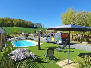 a pool with an umbrella and chairs and a van at Les 2 étangs de la Foulonnerie in Saint-Jean-Saint-Germain