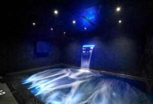 a swimming pool with a waterfall in a dark room at H Hotel & SPA - Adults Only in St. Julianʼs