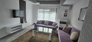 a living room with a purple couch and a tv at Apartman STARI GRAD in Bihać