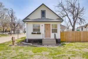 ein kleines weißes Haus mit einer Holztür in der Unterkunft Walk to Memorial Stadium Family Home with Patio in Lincoln