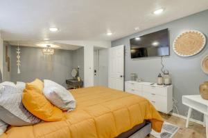 ein Schlafzimmer mit einem Bett mit gelber Bettwäsche und einem TV an der Wand in der Unterkunft Walk to Memorial Stadium Family Home with Patio in Lincoln