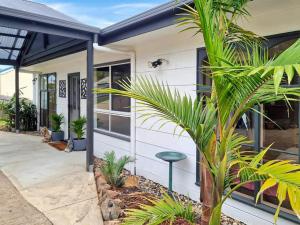 a house with palm trees in front of it at Holiday Home in Lakes Entrance! in Lakes Entrance