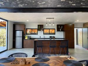 a kitchen with a bar with chairs and a table at Cabaña Nurela in Mazamitla