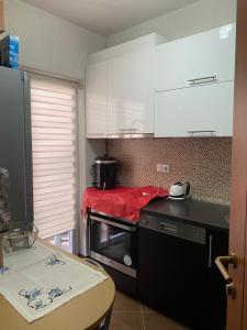 a kitchen with white cabinets and a table in it at Ralin Apart in Prizren