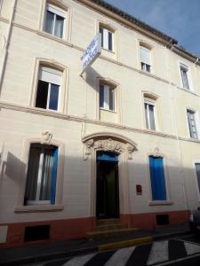 a white building with blue windows and a door at Hotel de France in Narbonne