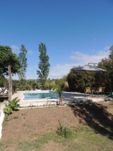 a pool with an umbrella and a table and chairs at Sampa Pacha - Cabaña 6 - Habitación privada in Bialet Massé