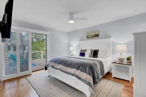 Un dormitorio blanco con una cama y un balcón. en Sandcrab Court 2 by Wild Dunes, with Amenities, en Isle of Palms