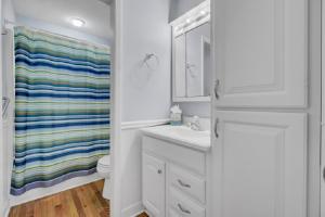 Un baño blanco con una cortina de ducha con rayas de arcoíris. en Sandcrab Court 2 by Wild Dunes, with Amenities, en Isle of Palms