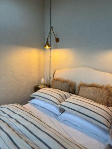ein Bett mit gestreiften Kissen in einem Zimmer mit einer Lampe in der Unterkunft The Old Sty in Canterbury