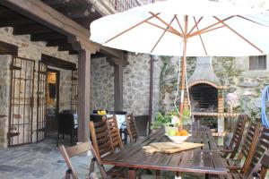 a wooden table with an umbrella on a patio at Cabachuelas I casas rurales in San Miguel de Valero