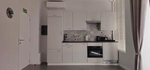 a kitchen with white cabinets and a stove at EMM Guesthouse in Ieper +3 photos
