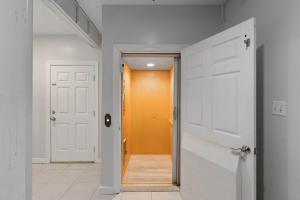 a hallway with an orange door and white walls at Beach Access with Elevator & FREE Activities in Gulf Shores +38 photos