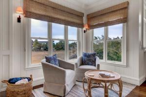 a living room with two chairs and a table and windows at Seagrass Lane 25 by Wild Dunes, Home with Marsh View and Resort Amenity Access in Isle of Palms +39 photos