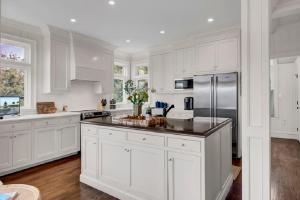 a white kitchen with white cabinets and a refrigerator at Seagrass Lane 25 by Wild Dunes, Home with Marsh View and Resort Amenity Access in Isle of Palms