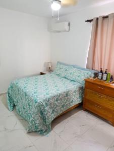 Un dormitorio con una cama y una cómoda de madera. en Acogedor apartamento a cerca de la playa, en San Felipe de Puerto Plata