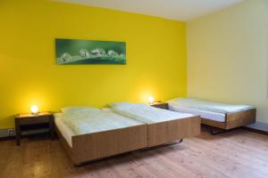 two beds in a room with yellow walls at Budget Waldhotel Unspunnen in Interlaken
