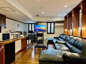 a living room with a leather couch and a kitchen at Windy Hill Morinoyado - Vacation STAY 83371v in Yamanakako