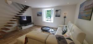 a living room with a couch and a television at Maison familiale Baylère - Piscine et spa - 8 pers in Buzy