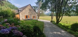 a stone house in a field with flowers at Maison familiale Baylère - Piscine et spa - 8 pers in Buzy