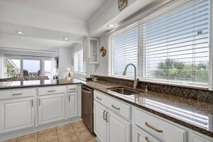 a kitchen with white cabinets and a sink and windows at Seagrove 11D by Wild Dunes, Oceanfront Condo in Isle of Palms