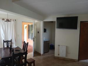 a dining room with a table and a television on a wall at Cabañas Los Cardales in Chascomús