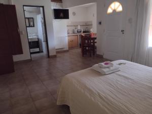 a bedroom with a white bed and a kitchen at Cabañas Los Cardales in Chascomús