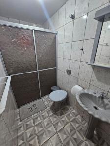 a bathroom with a shower and a toilet and a sink at Pousada Amigu's in Pontal do Paraná