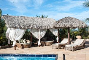 un complexe avec des chaises et des parasols et une piscine dans l'établissement Pousada Aruana, à Canoa Quebrada