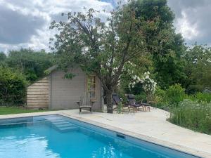 a swimming pool with two chairs and a house at Cute cob cottage in Winterborne Stickland +16 photos