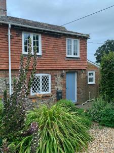 a brick house with a white door at Cute cob cottage in Winterborne Stickland