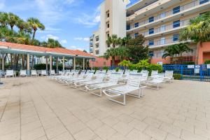 a row of white lawn chairs in front of a building at Coastal 3-bed 2-bath Condo-new Smyrna Beach Fl in New Smyrna Beach