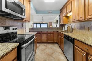 a large kitchen with wooden cabinets and black appliances at Litchfield By the Sea 3BR Tranquil Retreat in Pawleys Island