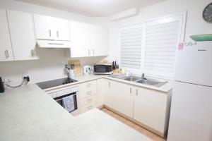 Una cocina blanca con fregadero y refrigerador. en Campbells Cove Unit 12, en Caloundra