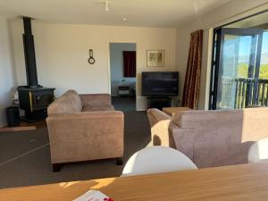 Diamond HarbourにあるCharteris Bay Holiday Houseのリビングルーム(ソファ、暖炉、テレビ付)