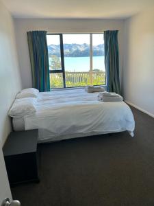 Diamond HarbourにあるCharteris Bay Holiday Houseのベッドと大きな窓のある寝室