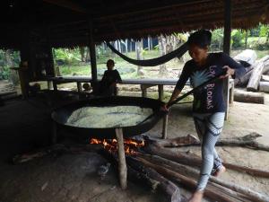 a woman is cooking food in a large grill at Hospedaje KOWAPANA BOCAS DE AMACAYACU in San Martín