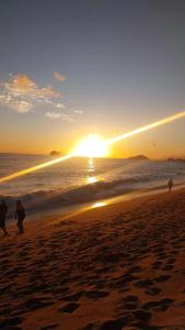 a group of people walking on the beach at sunset at "Refúgio Lima" in São Sebastião