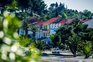 a large building with palm trees in front of it at Apartments Maestral in Trpanj