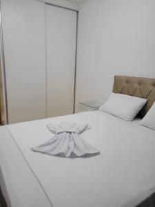 a white bed with a bow on top of it at Egidios AP - Centro de São Pedro da Aldeia in São Pedro da Aldeia