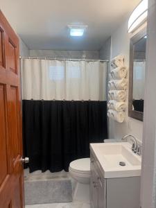 a bathroom with a toilet and a black shower curtain at Cape Cod Hyannis Rendezvous' in Barnstable +29 photos