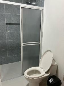 a bathroom with a toilet with a glass shower at Hostal La Cabaña Tayrona in Santa Marta