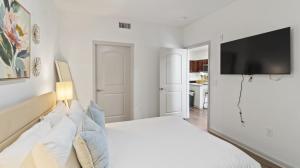 Un dormitorio blanco con una cama y un televisor de pantalla plana. en Cozy 1bd Apartment, en Frisco