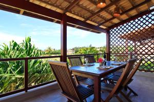 una mesa de madera y sillas en un balcón con vistas en Pipa Beleza Chalé Particular, en Pipa