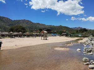 a sandy beach with a playground and some mountains at Casa doña tati in Cortaderas